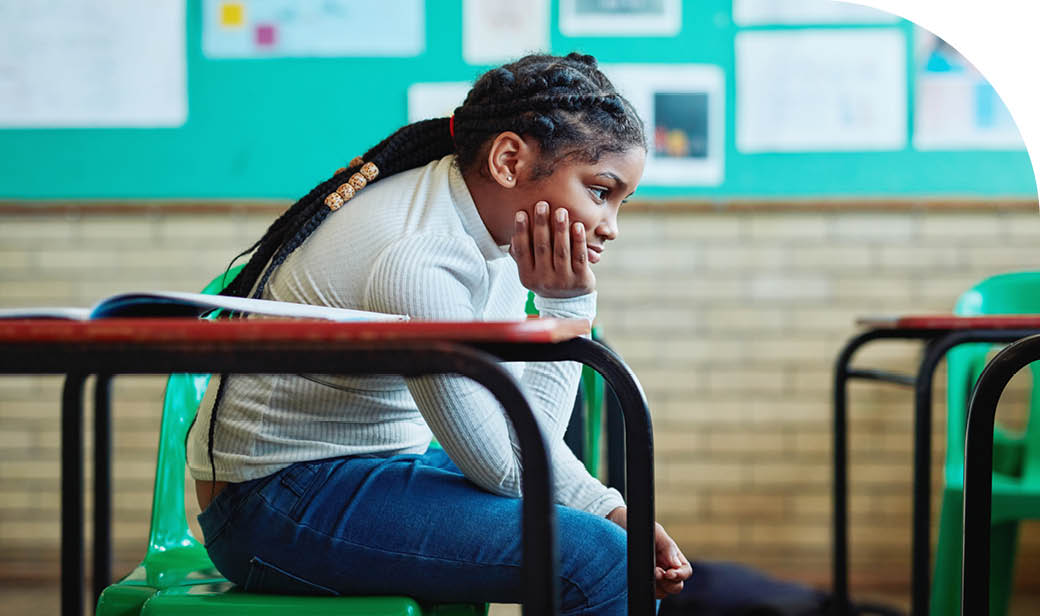 Shot of a young girl looking bored at her desk in a classroom